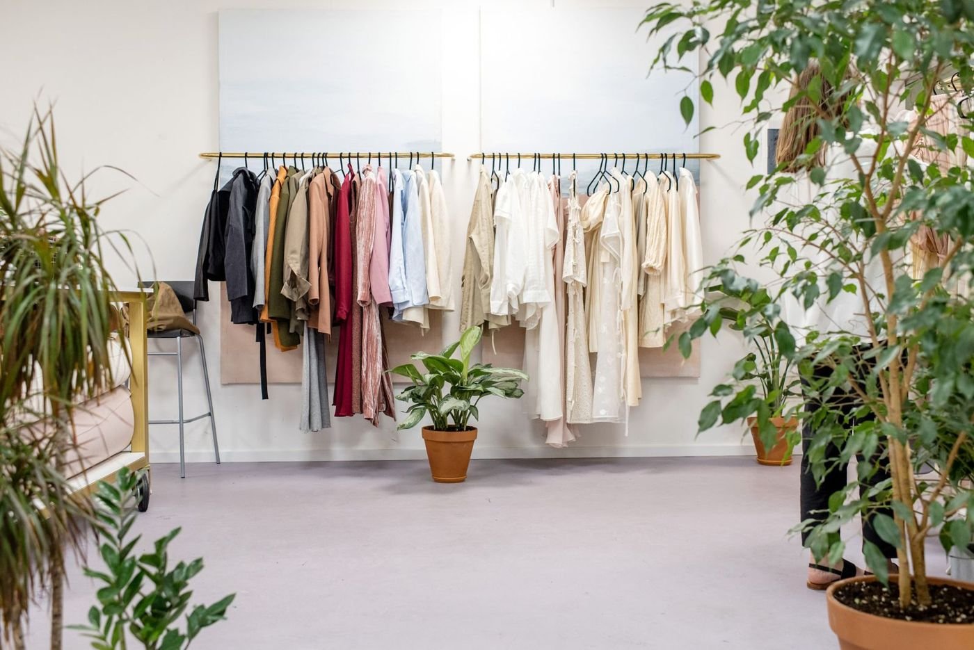 Clothes hanging on a rail in a bright shop with plants