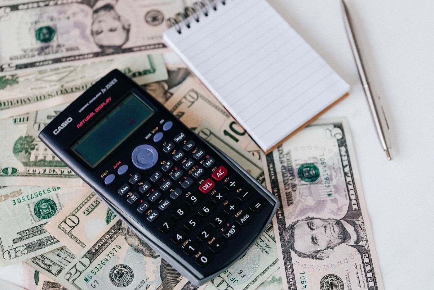 A calculator, notepad and banknotes on a desk