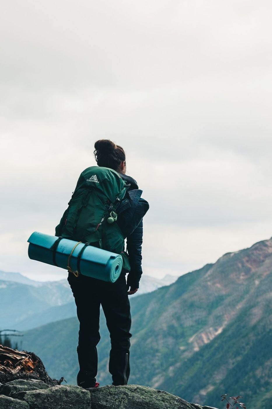 A hiker with a backpack looking over a mountain valley
